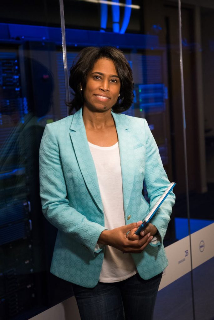 Confident woman in a server room, holding a tablet. Ideal for tech and business themes.